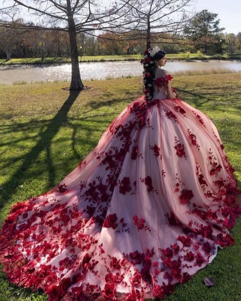 Woman in burgundy and blush ball gown by a lake